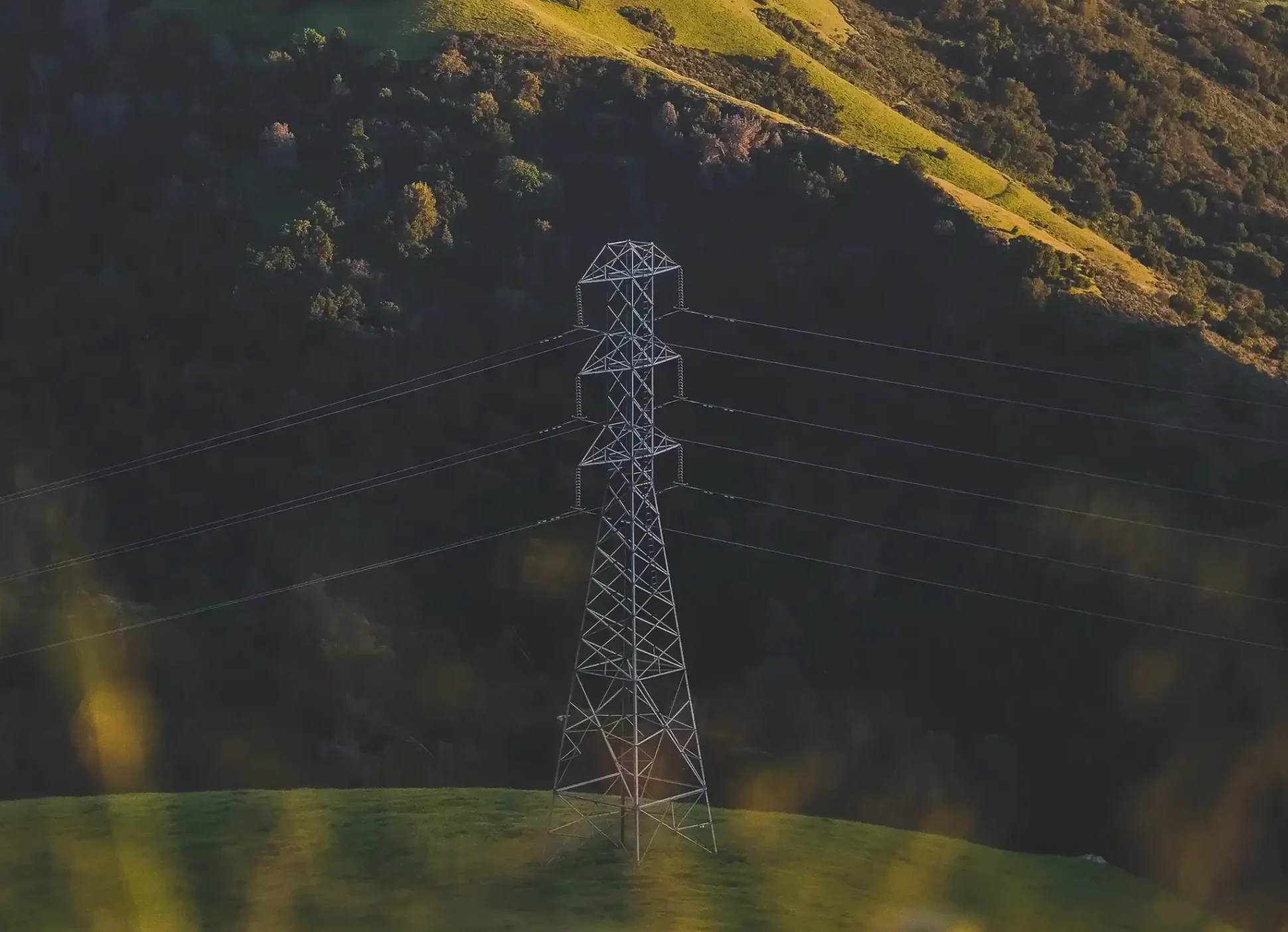 vertical-shot-electric-tower-grassy-mountain_1_11zon